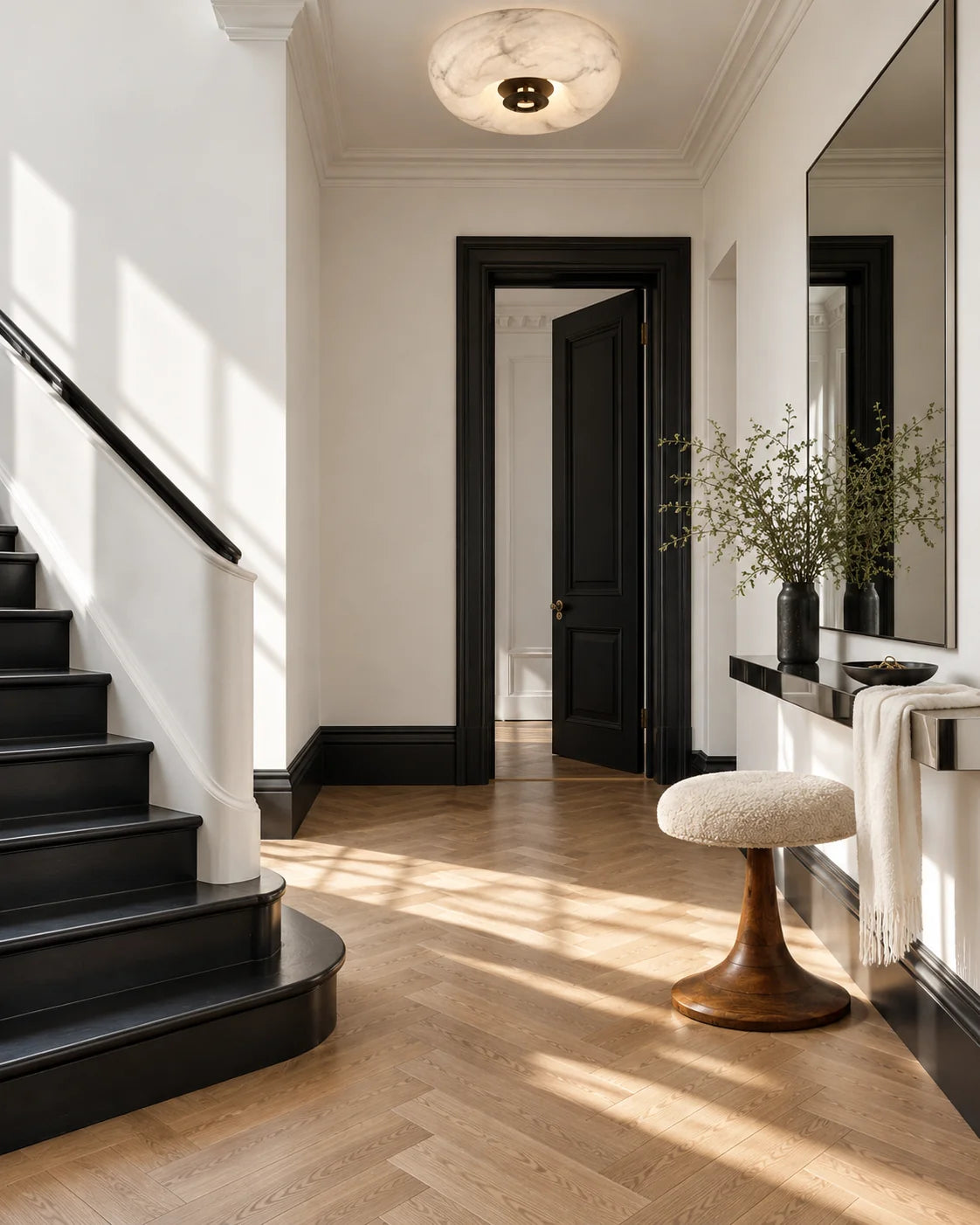 Noir et blanc — Miro et Vela apportent des formes rondes entre escalier, portes et parquet en chevrons.